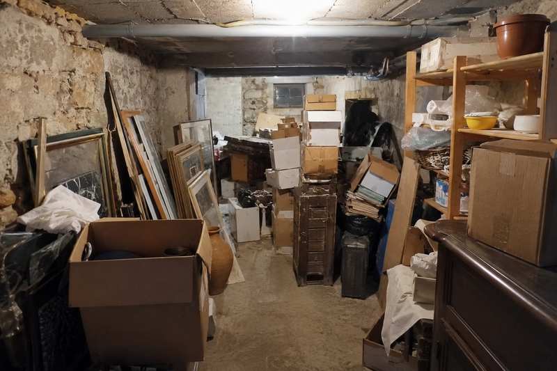 Cave de sous-sol encombrée de cartons, cadres et objets